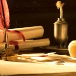 Old parchment on a desk with a quill, ink, and a unlit candle