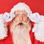 image of santa claus in his red suit in front of a red background with a surprised look on his face